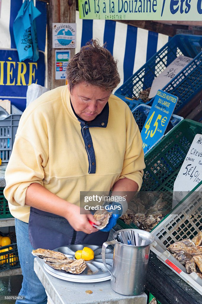 Woman preparing the oysters at a local market in France