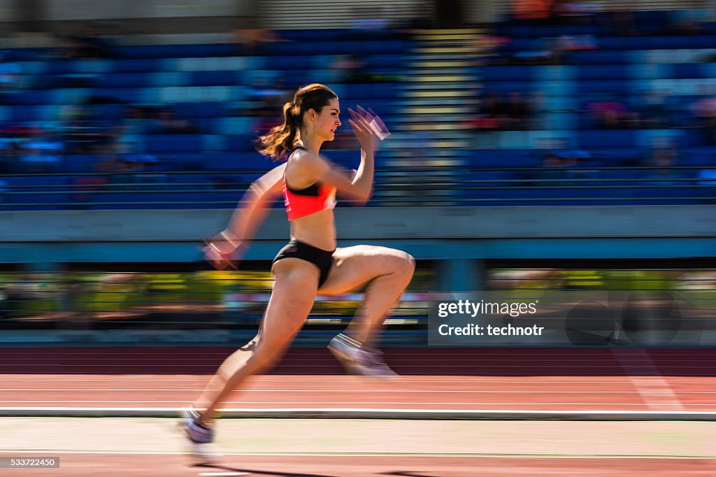 Young attractive female athlete at long jump, pannig shot