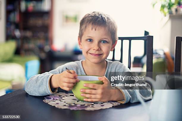 happy little boy eating breakfast cereal - boy eating cereal stock pictures, royalty-free photos & images