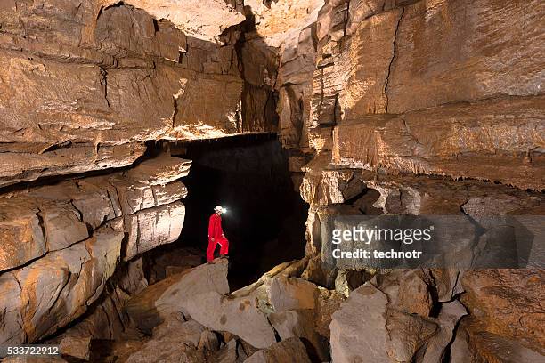 caver posing in beautiful cave against dark background - speleology stock pictures, royalty-free photos & images