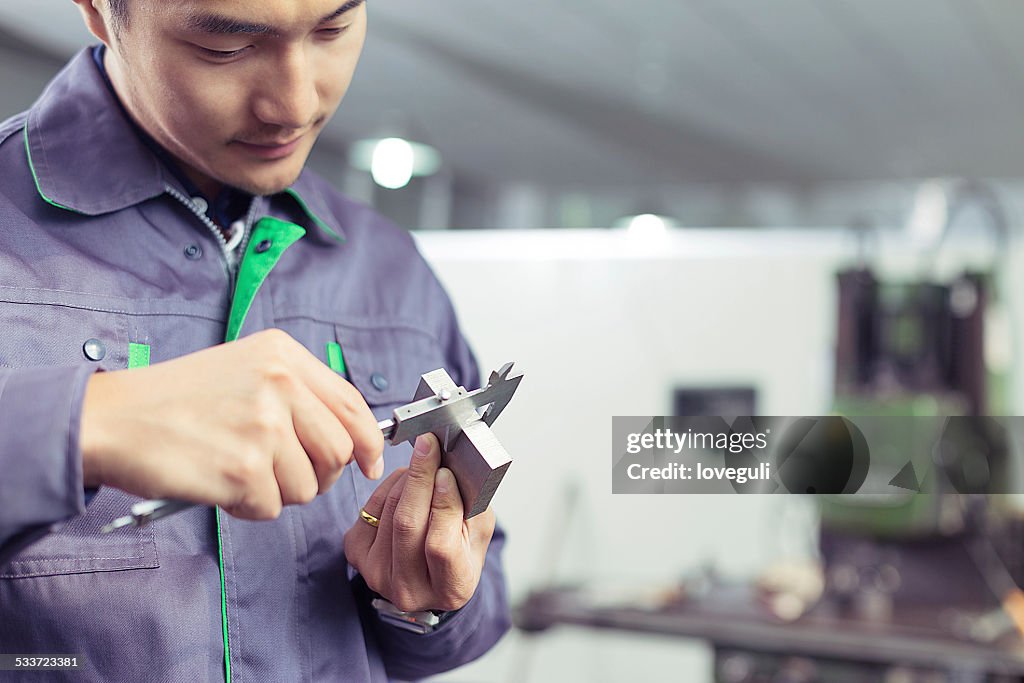 Asian mechanic worker measure spare part in  factory