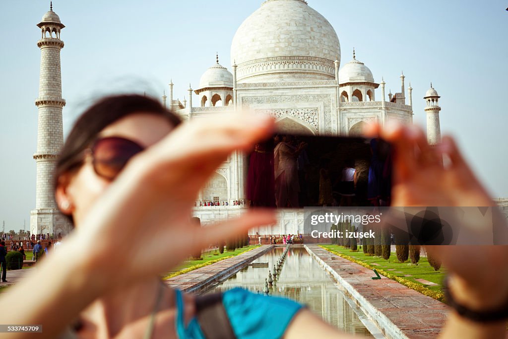 Female tourist taking selfie with Taj Mahal