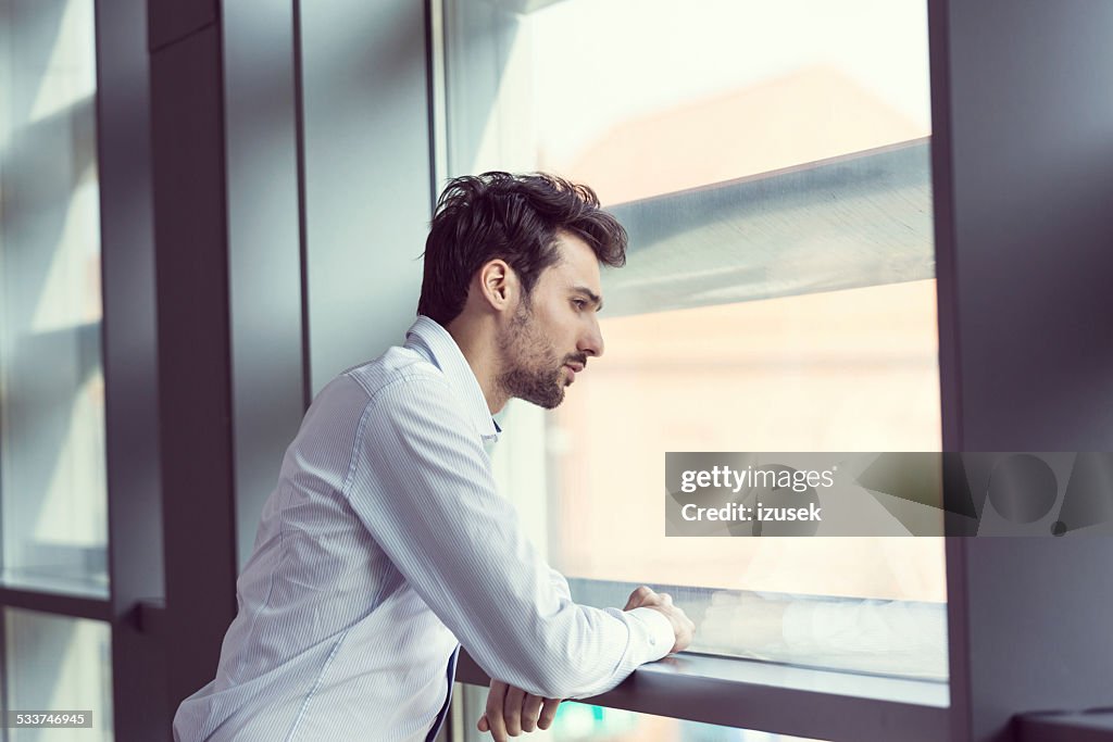 Jovem empresário, olhando para fora da janela