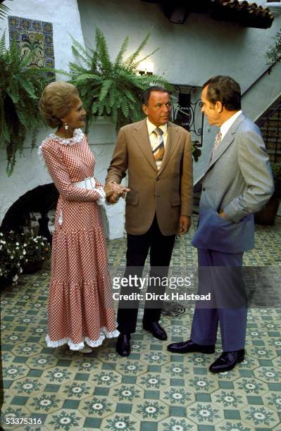 First Lady Pat Nixon, entertainer Frank Sinatra & President Richard Nixon chatting during a GOP celebrity fundraising event at Nixon's home.