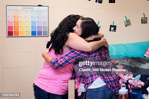 College student hugging mother in dormitory room College student hugging mother in dormitory room