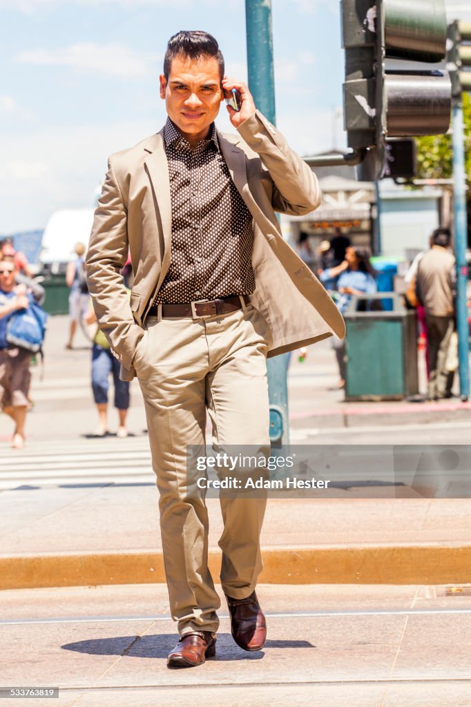 Hispanic businessman talking on cell phone in urban crosswalk