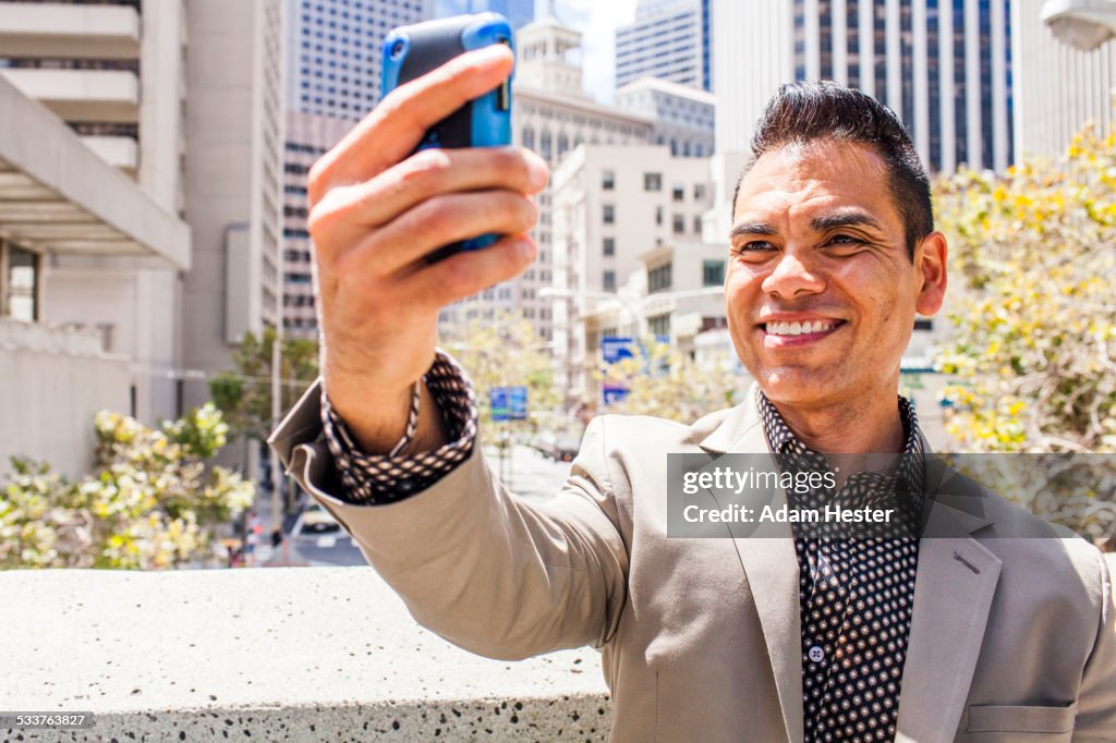 Hispanic businessman taking cell phone selfie