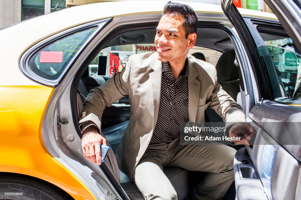 Hispanic businessman exiting taxi