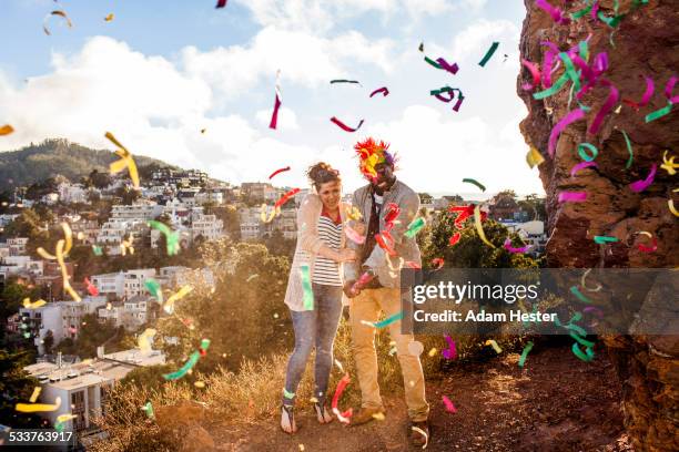 couple throwing confetti on hill overlooking cityscape - dodging stock pictures, royalty-free photos & images