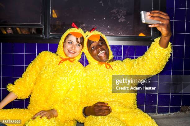 couple taking cell phone selfies wearing chicken costumes - multikulturalismus stock-fotos und bilder