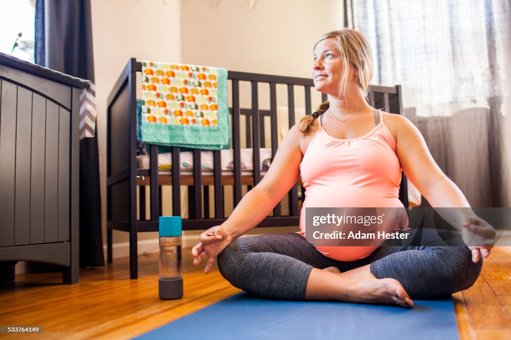 Pregnant Caucasian woman meditating in nursery