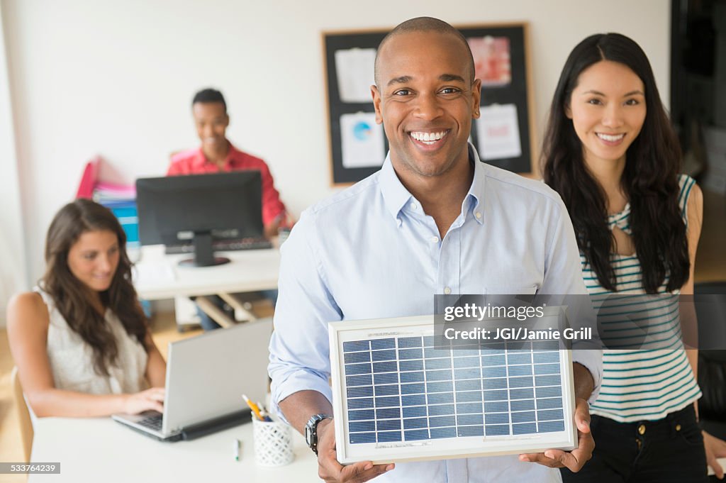Businessman holding solar panel model in office