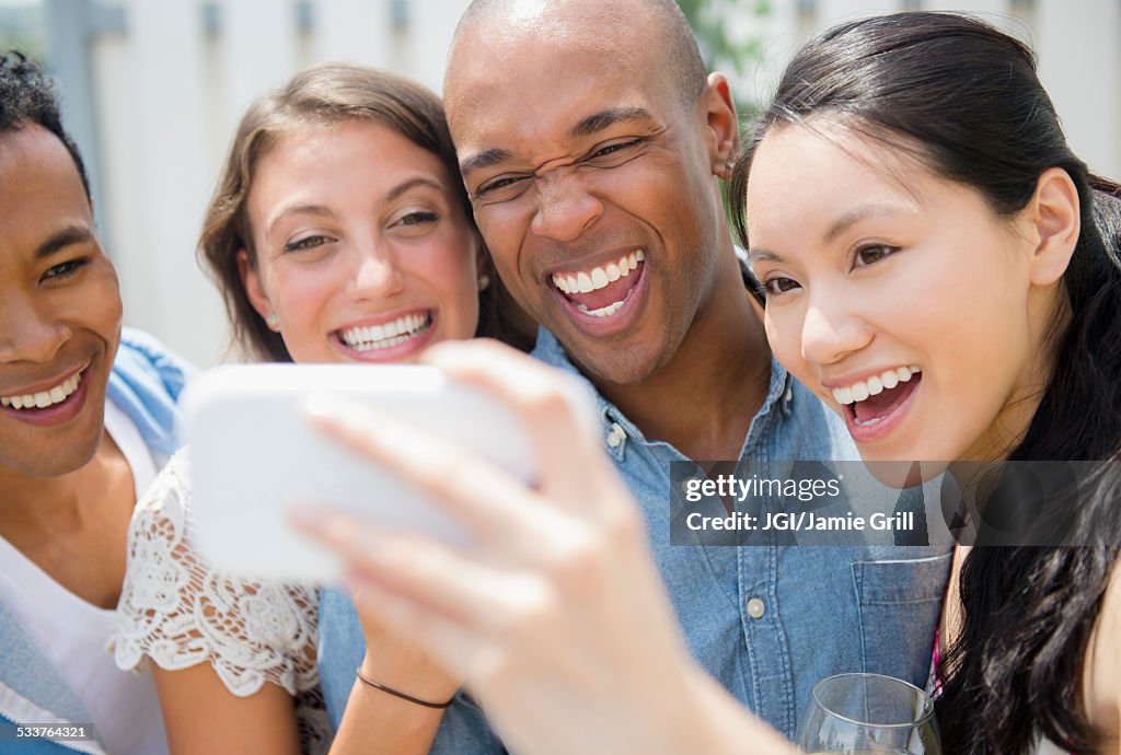 Friends taking cell phone photograph at party