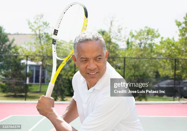 african american man playing tennis on court - holding tennis racquet stock pictures, royalty-free photos & images