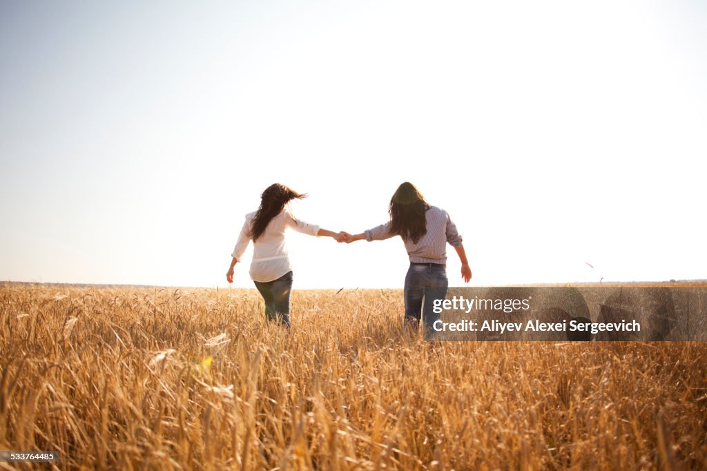Caucasian women holding hands in rural field