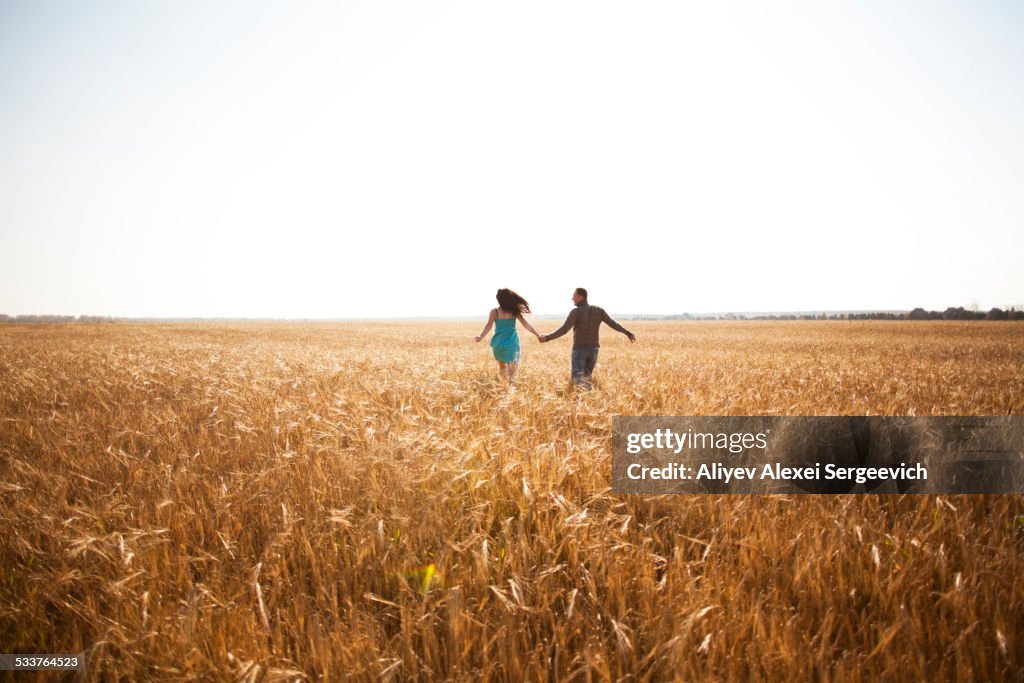 Caucasian couple running in rural field