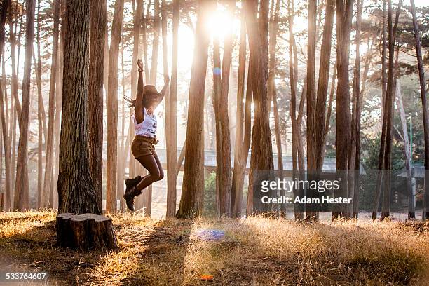 black woman jumping from stump in sunny forest - thick black woman 個照片及圖片檔