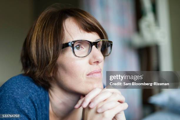 caucasian woman thinking with hands clasped - lingering fotografías e imágenes de stock