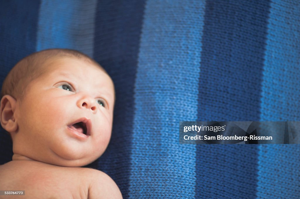 Close up of newborn mixed race baby laying on striped blanket