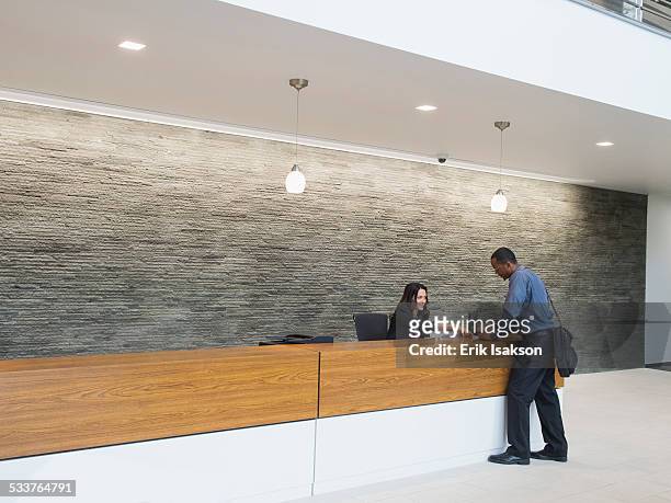 businessman talking to receptionist at office front desk - hotel check in stock pictures, royalty-free photos & images