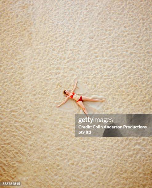 high angle view of pacific islander woman making sand angel on beach - angel hot - fotografias e filmes do acervo