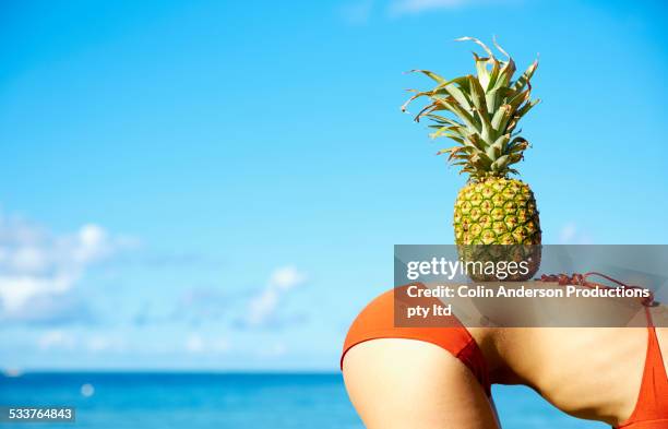 Pacific Islander woman balancing pineapple on back