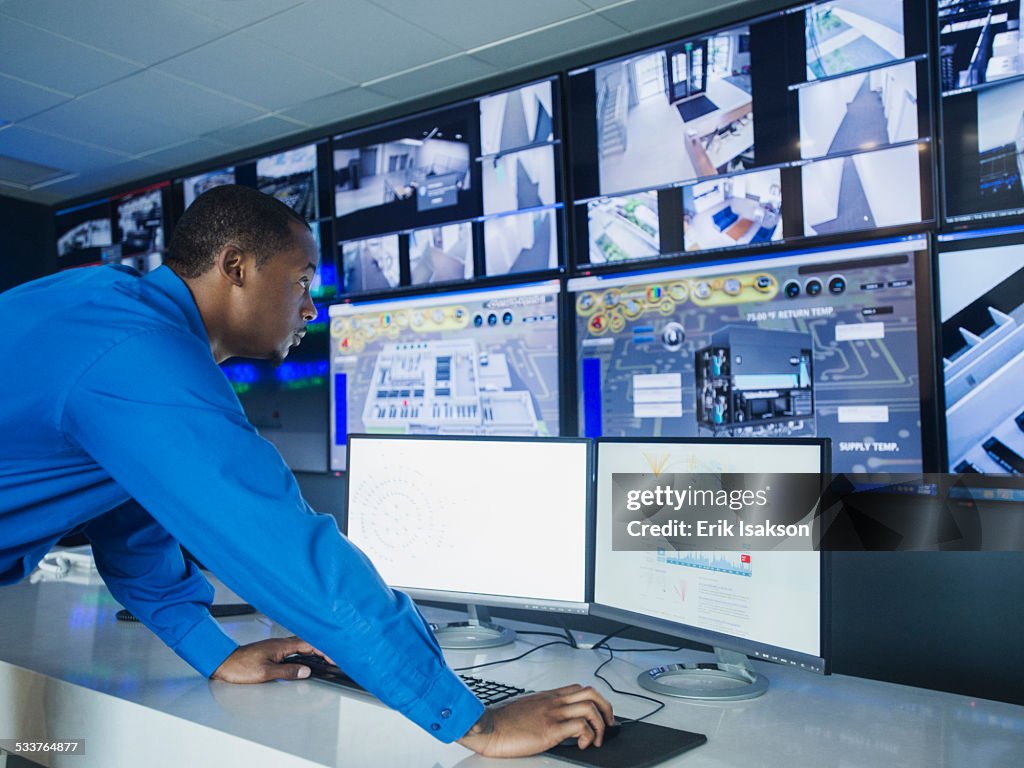 Black security officer watching surveillance cameras