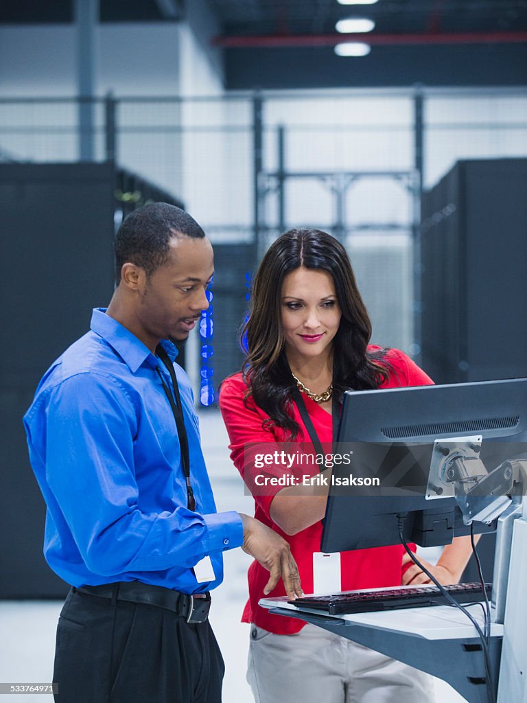 Business people using computer in server room