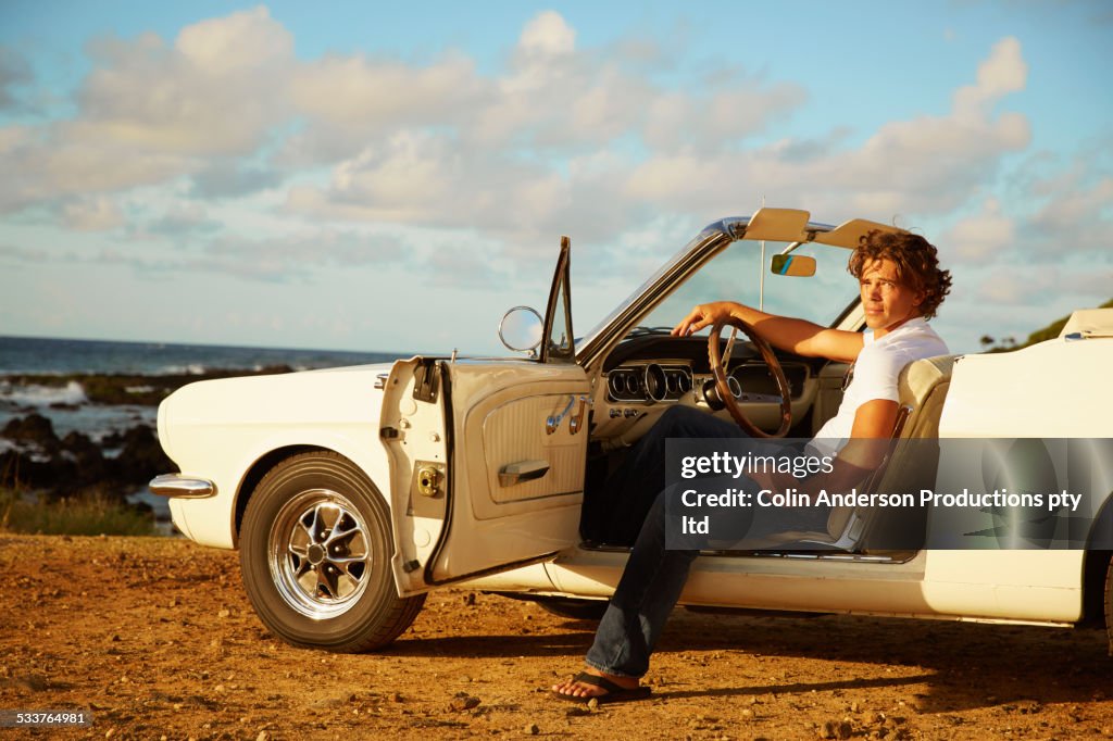 Caucasian man relaxing in convertible on beach
