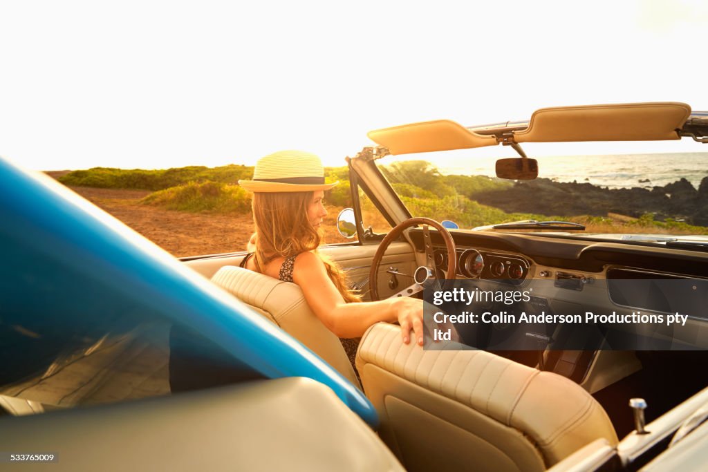 Caucasian woman relaxing in convertible on beach