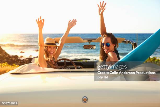 women cheering in convertible on beach - classic day 2 stock-fotos und bilder