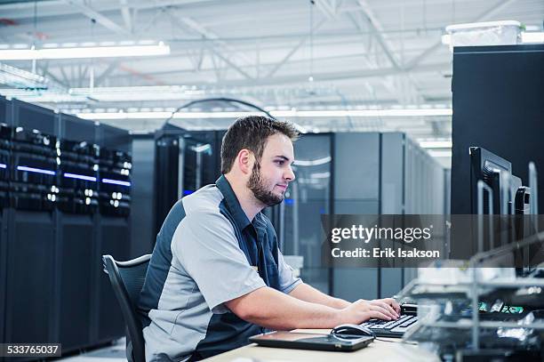 caucasian technician using computer in server room - server professional stock-fotos und bilder