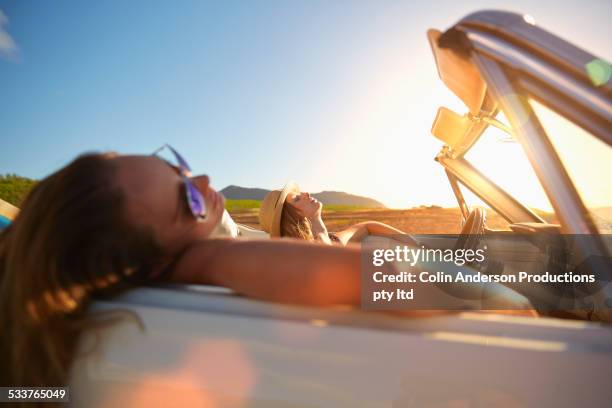 women relaxing in convertible on beach - sleeping in car stockfoto's en -beelden