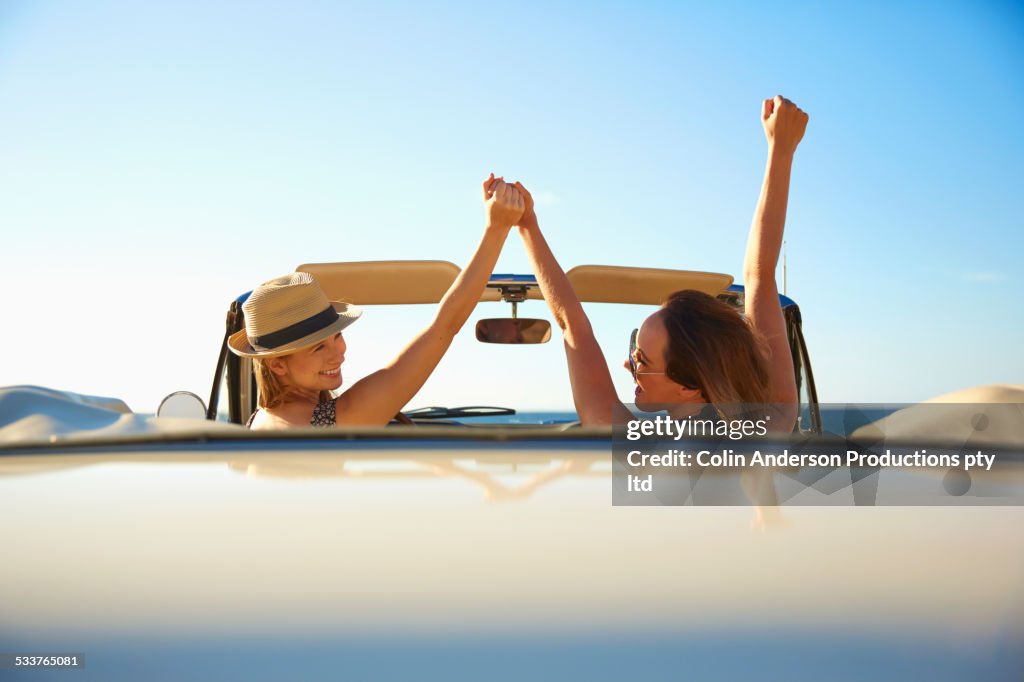 Women cheering in convertible outdoors