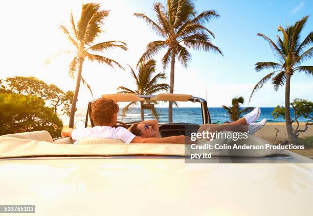 couple relaxing in convertible on beach - classic day 2 stockfoto's en -beelden