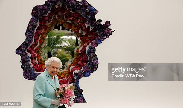 Queen Elizabeth II is pictured next to a floral exhibit by the New Covent Garden Flower Market, which features an image of the Queen, at Chelsea...