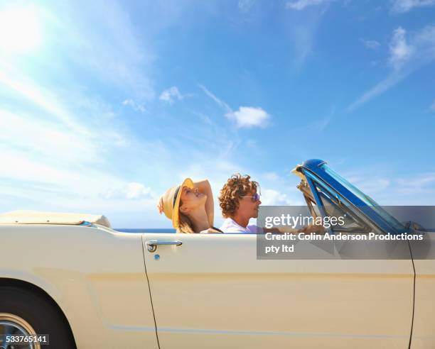 caucasian couple driving convertible under blue sky - auto convertibile photos et images de collection