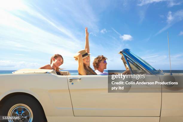 friends driving convertible under blue sky - 3 guy friends road trip stock-fotos und bilder