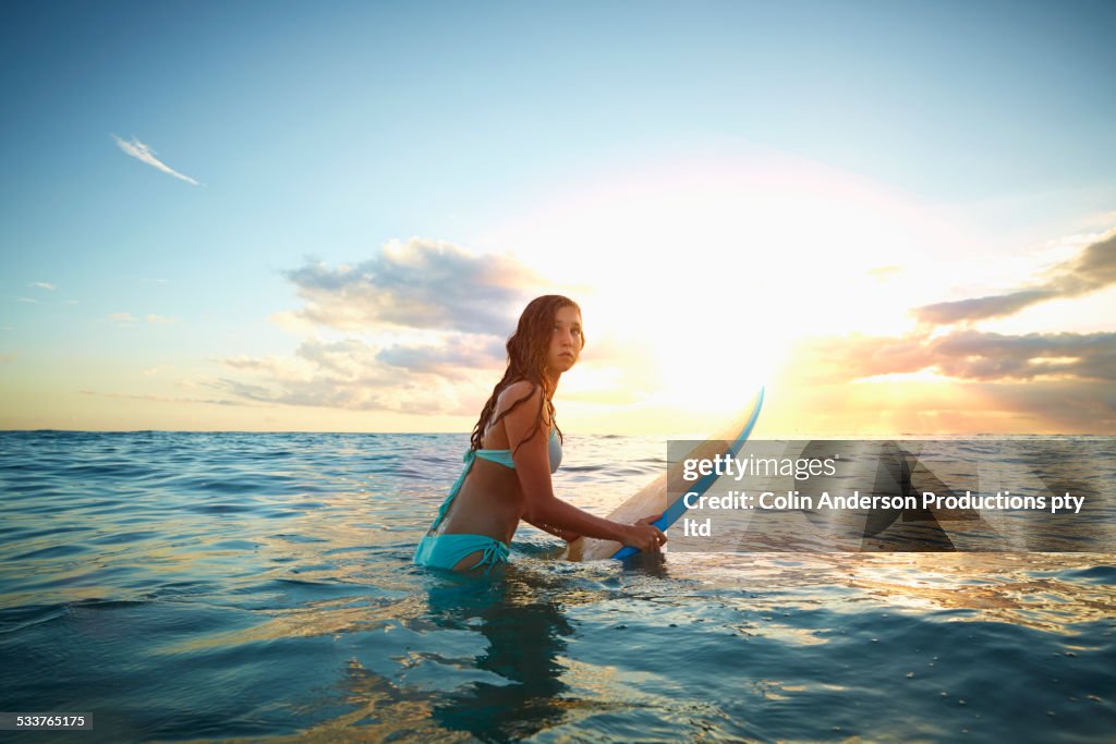 Caucasian girl carrying surfboard in ocean