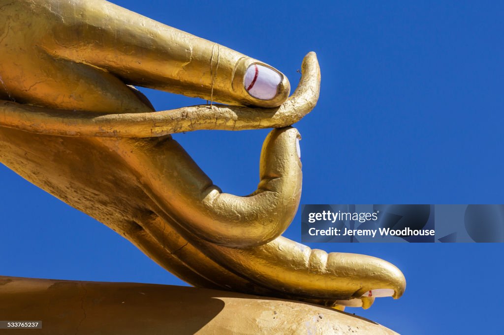 Close up of golden hand statue against blue sky