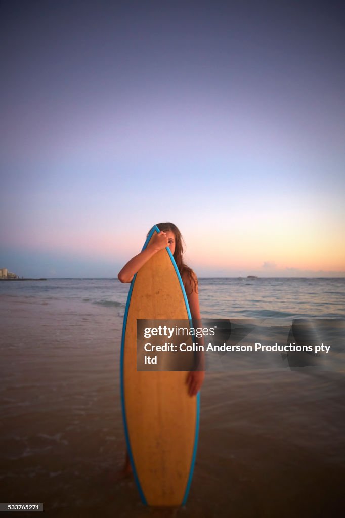 Caucasian girl holding surfboard on beach