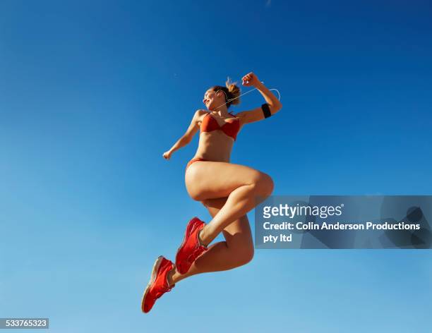 pacific islander woman jumping for joy under blue sky - melody anderson stockfoto's en -beelden