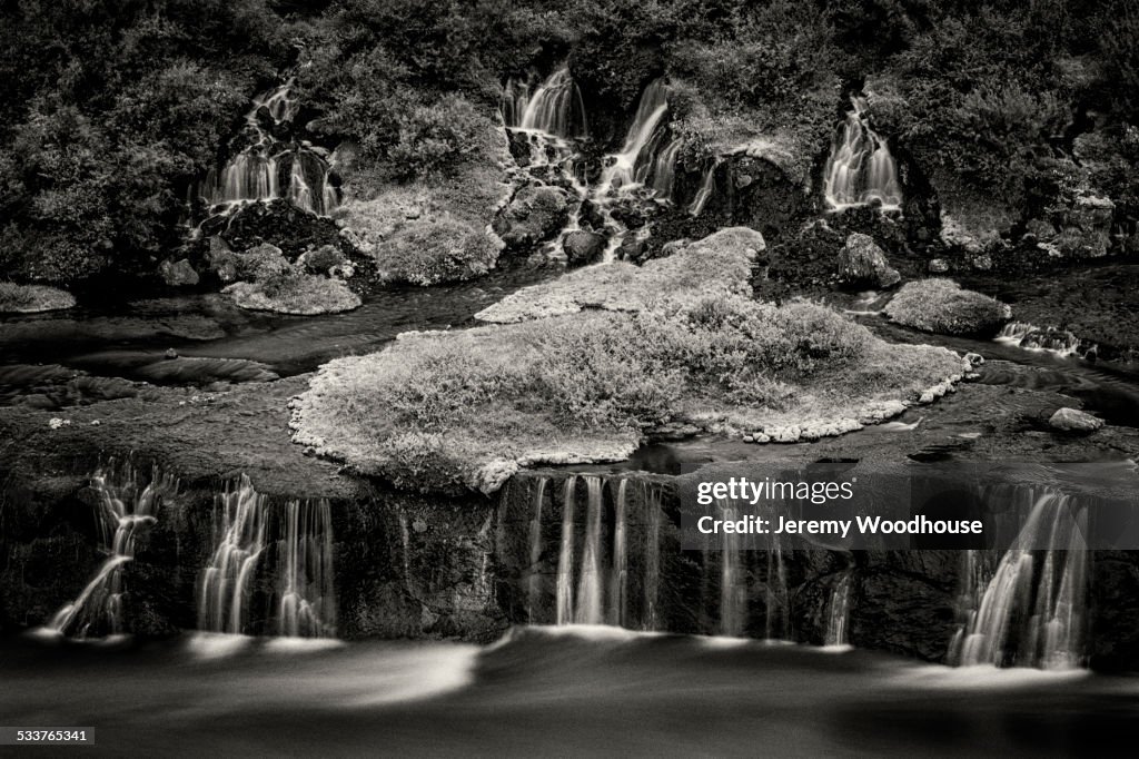 Waterfall flowing over rock formations to lake