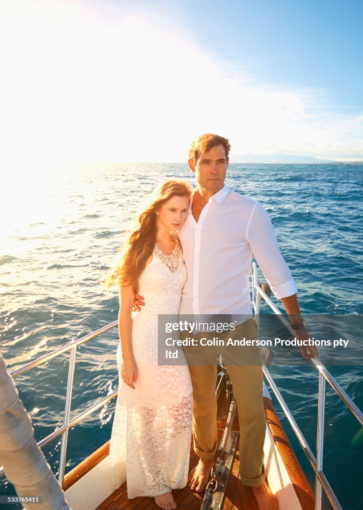 Caucasian couple standing on yacht deck