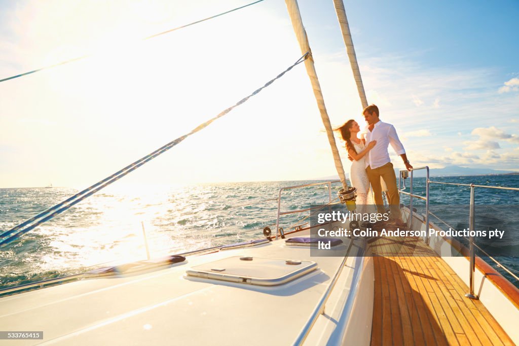 Caucasian couple hugging on yacht deck