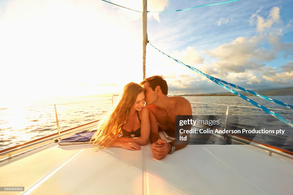 Caucasian couple sunbathing on yacht deck