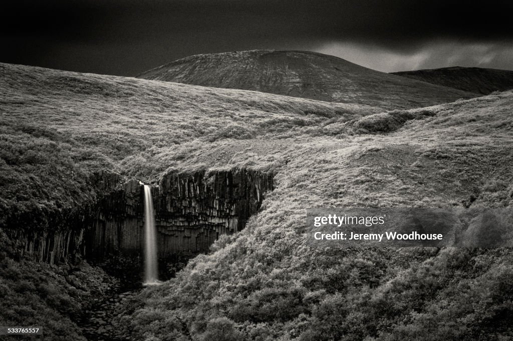 Waterfall in rolling hills in remote landscape