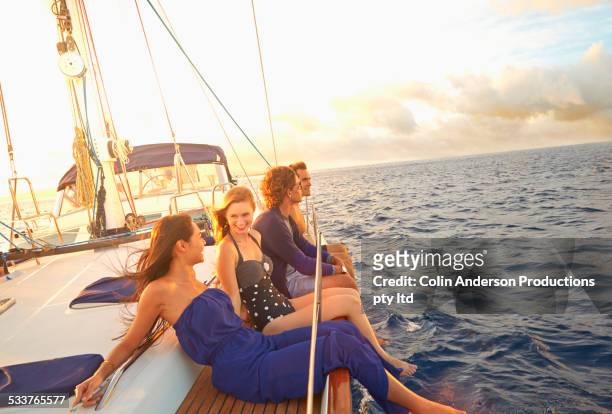 friends dangling legs over yacht deck - hot women on boats stock-fotos und bilder