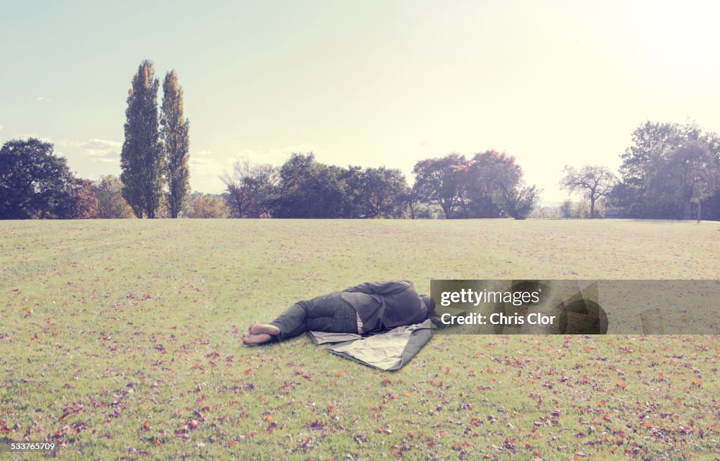 Man napping on coat in park field