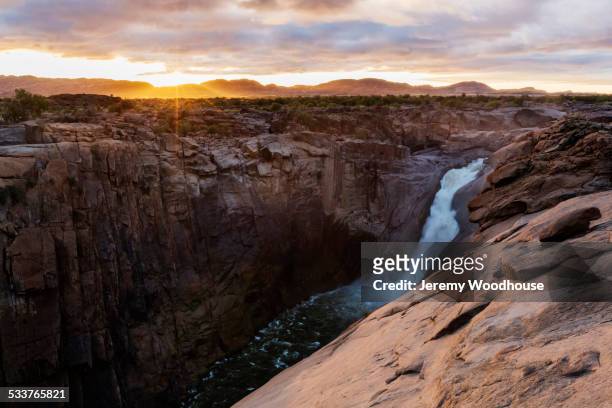 waterfall flowing over rocky cliffs in remote landscape - oranje stock-fotos und bilder